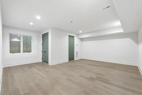 a view of an empty room with window and wooden floor