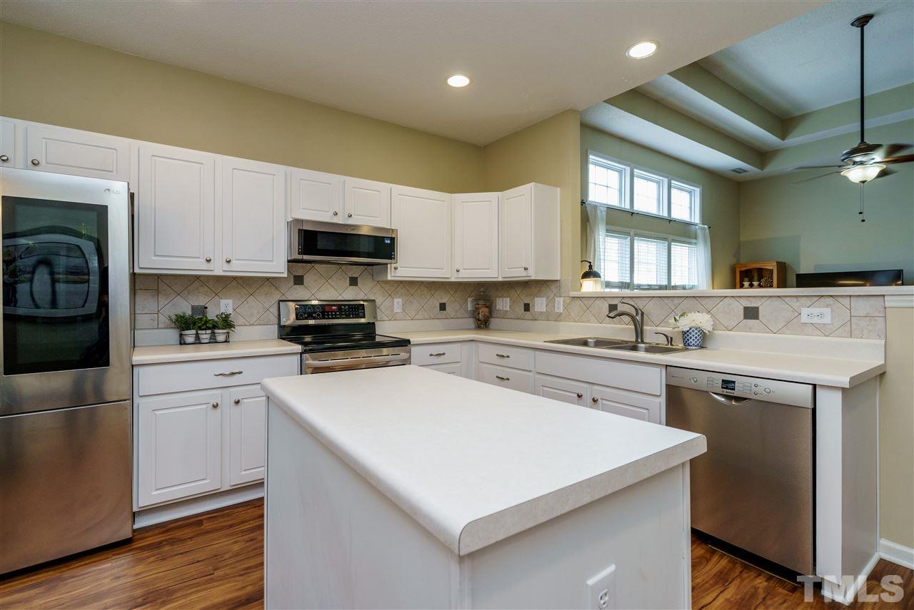 4848 Tommans Trail Raleigh, NC 27616 - Photo 12 of 22 a kitchen with a sink a stove a refrigerator a center island and cabinets