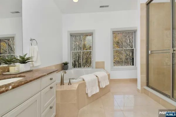 a spacious bathroom with a tub sink and mirror