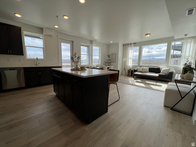 718 West Blue Magic Lane, Unit S201 Midvale, UT 84047 - Photo 16 of 18 Kitchen featuring dark cabinetry, a center island, stainless steel dishwasher, light wood finished floors, and open floor plan