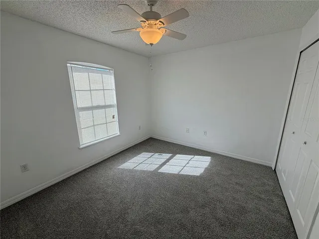 an empty room with windows and chandelier fan