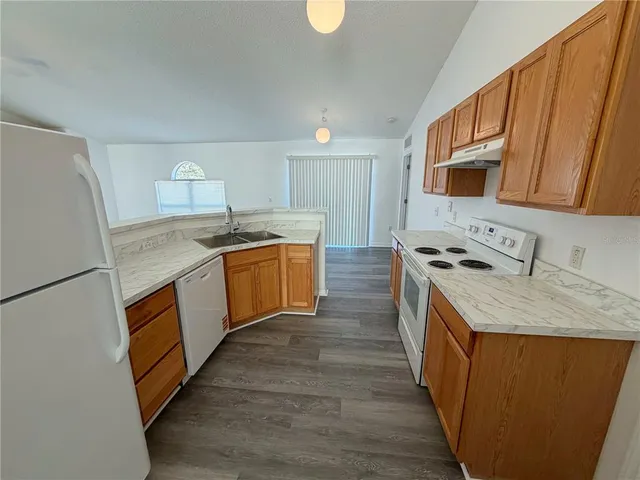 a kitchen with stainless steel appliances granite countertop a sink a stove a refrigerator a washer dryer and white cabinets