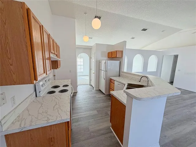 a view of a kitchen with a sink dishwasher stove and wooden cabinets