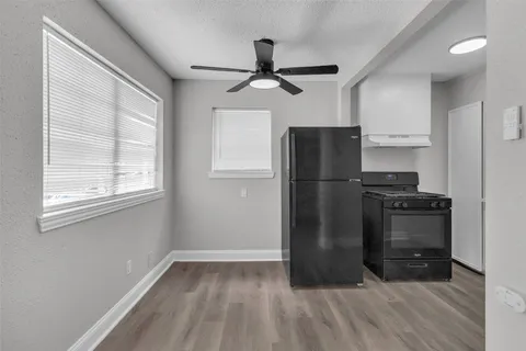 an empty room with wooden floor ceiling fan and windows