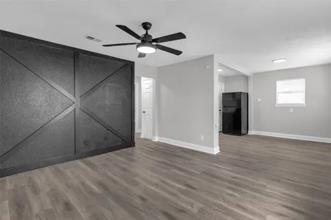 an empty room with wooden floor fan and windows