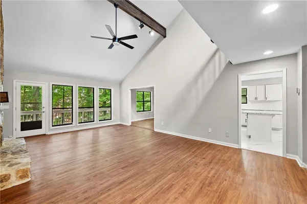 an empty room with wooden floor a ceiling fan and windows