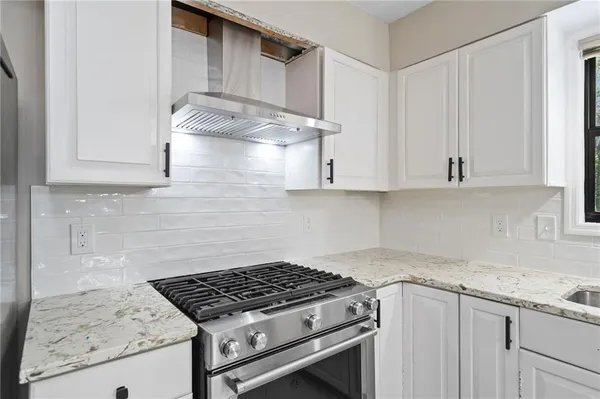 a kitchen with granite countertop stainless steel appliances stove top oven and cabinets