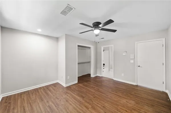 an empty room with wooden floor and ceiling fan