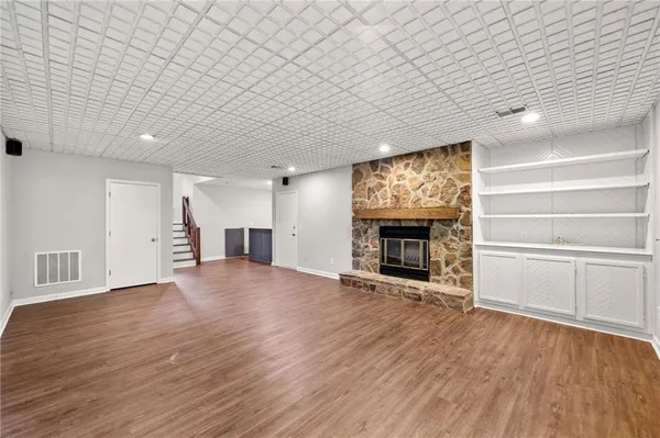 an empty room with wooden floor fireplace and windows