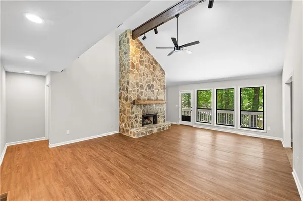 a view of an empty room with wooden floor fireplace and a window