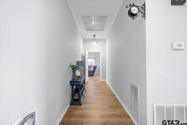 a view of a hallway with wooden floor and a bathroom