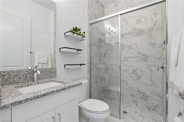 a bathroom with a granite countertop sink a toilet and shower