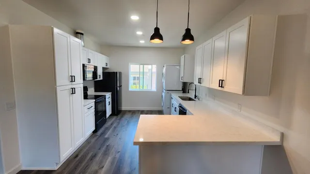 a large kitchen with stainless steel appliances a large counter top a refrigerator a sink a stove a microwave and a refrigerator