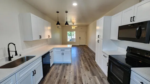 a kitchen with granite countertop a stove a sink and wooden floor