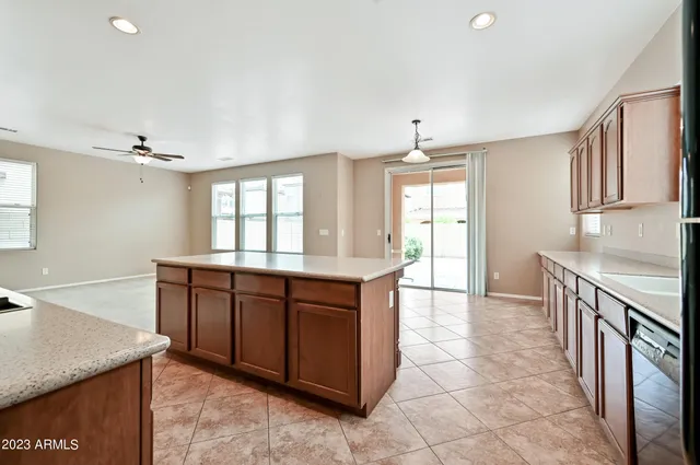 a large kitchen with kitchen island granite countertop a stove a sink a refrigerator and white cabinets with wooden floor