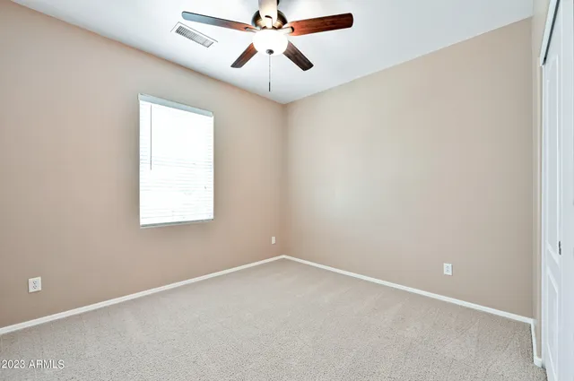 an empty room with a window and a fan