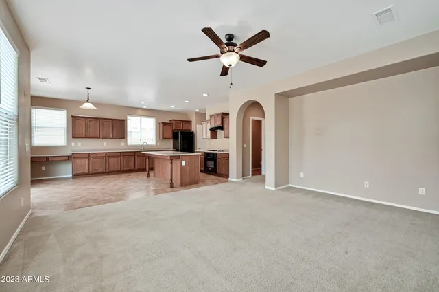 an open kitchen with refrigerator and ceiling fan