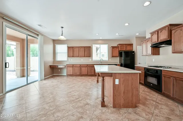 a large kitchen with stainless steel appliances kitchen island granite countertop a sink and a stove