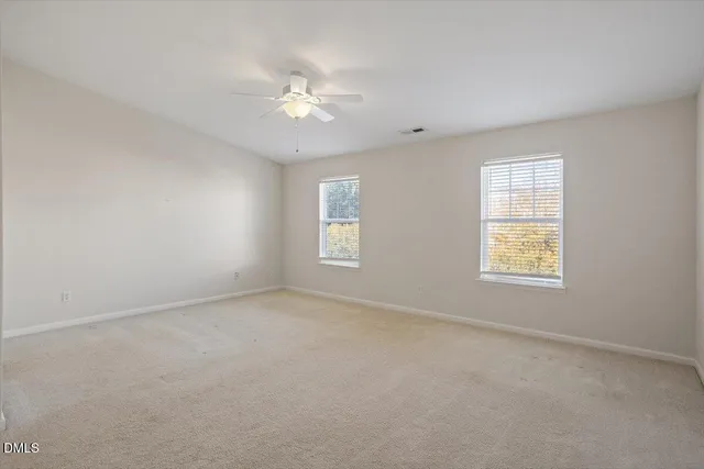an empty room with windows and fan