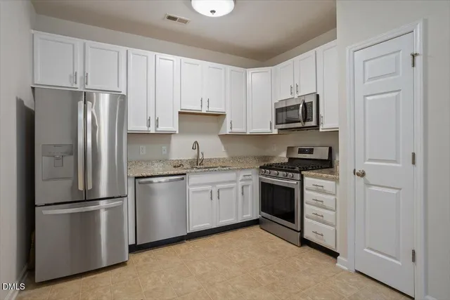 a kitchen with cabinets stainless steel appliances and a counter space