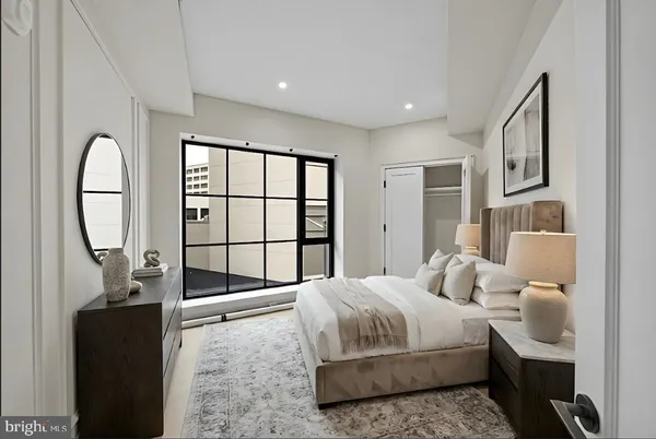 a bedroom with a bed a mirror and a large window