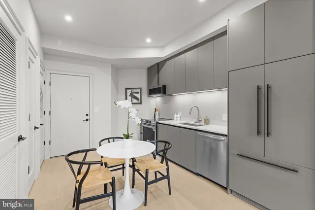 a kitchen with stainless steel appliances a dining table chairs and white cabinets