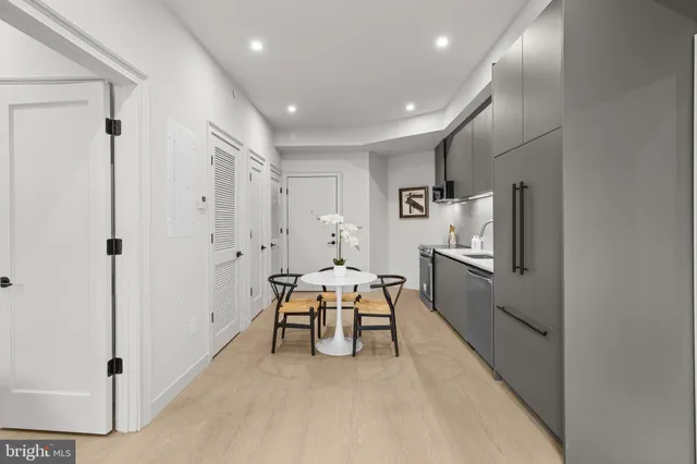 a living room with furniture a large window and stainless steel appliances