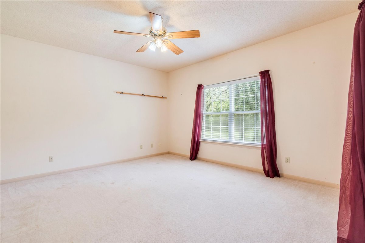 19106 Eyerley Road Manor, TX 78653 - Photo 18 of 40 second bedroom on main level with a refreshing ceiling fan and ample natural illumination from a wide window.