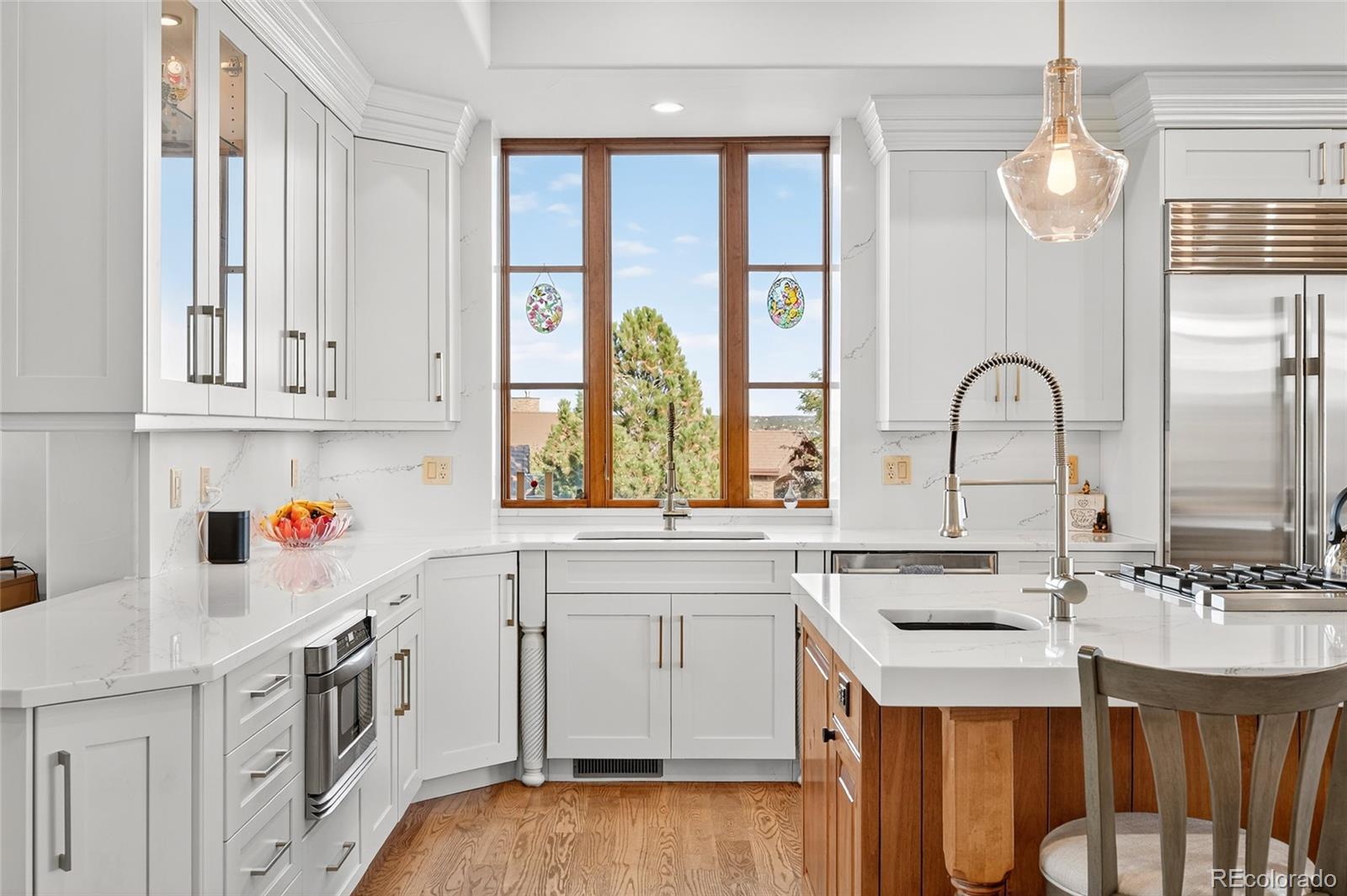 5001 Raintree Circle Parker, CO 80134 - Photo 20 of 50 a kitchen with stainless steel appliances granite countertop a stove a sink dishwasher and white cabinets with wooden floor