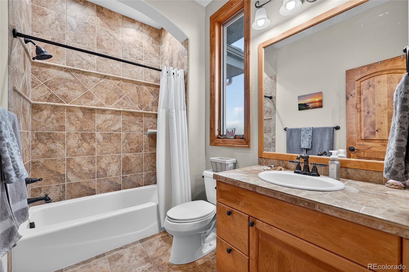 5001 Raintree Circle Parker, CO 80134 - Photo 36 of 50 a bathroom with a granite countertop sink a toilet a mirror a vanity and bathtub