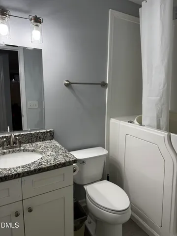 a bathroom with a granite countertop toilet sink and mirror