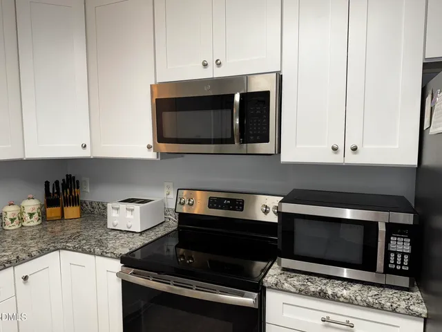a kitchen with granite countertop a stove and a microwave