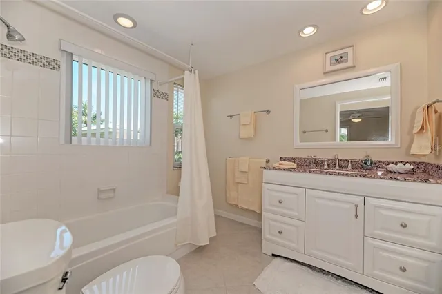 a bathroom with a granite countertop sink toilet tub and mirror