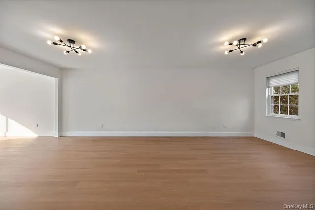 a view of an empty room with chandelier fan