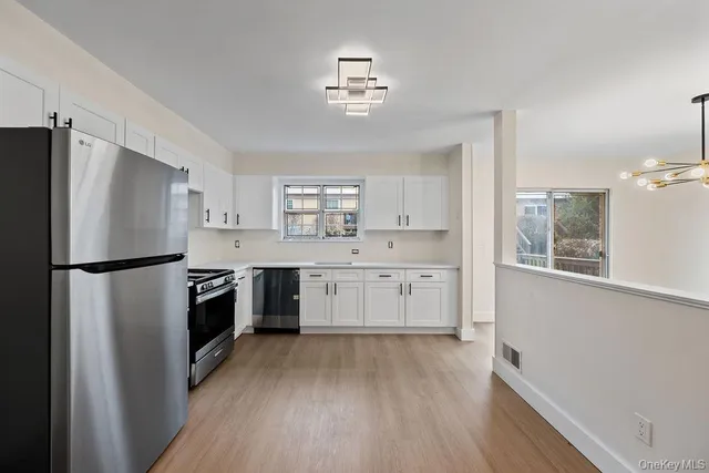 a kitchen with a refrigerator a sink and dishwasher with wooden floor