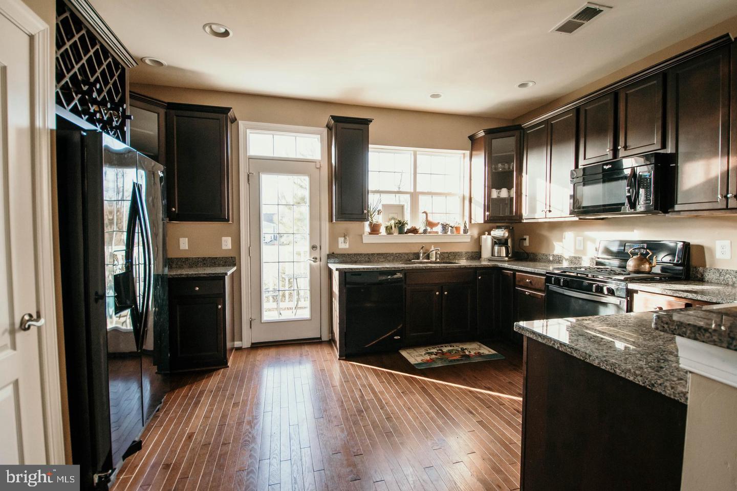 7454 Riding Meadow Way Manassas, VA 20111 - Photo 4 of 21 a kitchen with stainless steel appliances granite countertop a refrigerator a sink dishwasher a stove and white countertops with wooden floor
