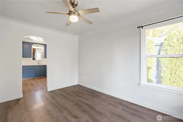 an empty room with wooden floor fan and windows