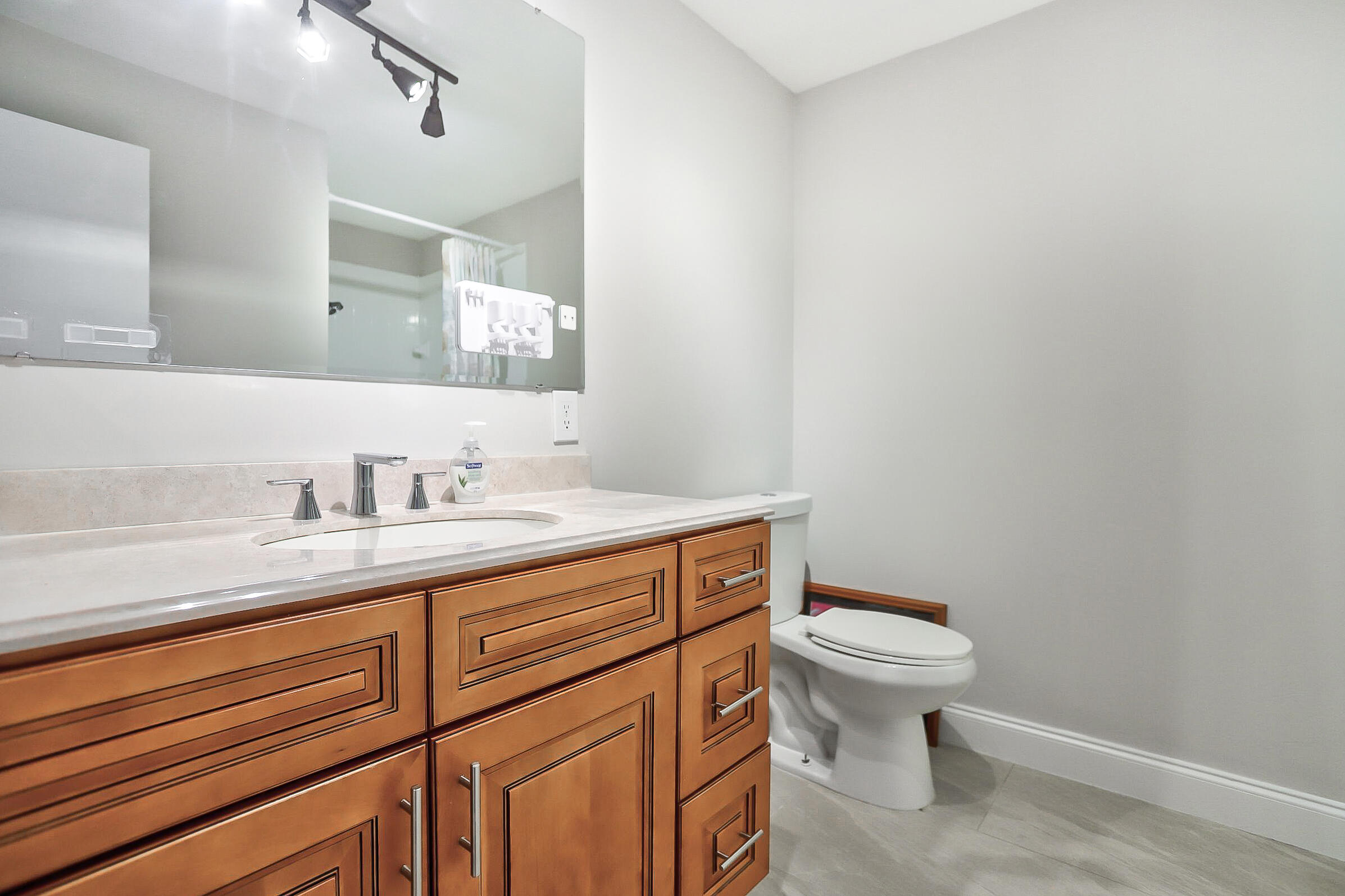 1169 Northwest 13th Street, Unit 1 Boca Raton, FL 33486 - Photo 13 of 20 a bathroom with a granite countertop toilet sink mirror and vanity
