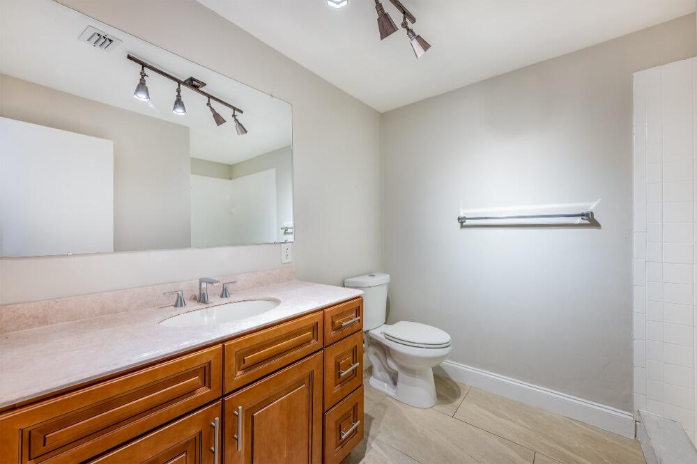 1169 Northwest 13th Street, Unit 1 Boca Raton, FL 33486 - Photo 9 of 20 a bathroom with a sink a toilet a mirror and shower