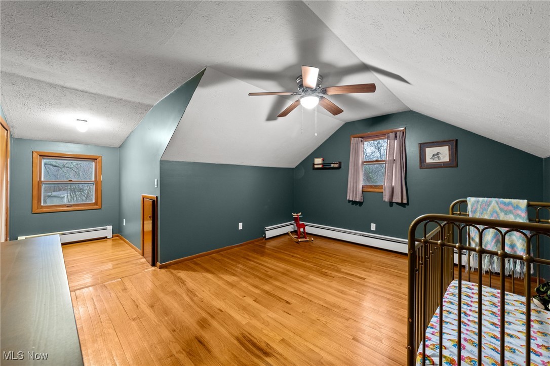 24659 Snell Road Columbia Station, OH 44028 - Photo 26 of 39 Bedroom featuring a textured ceiling, ceiling fan, a baseboard radiator, hardwood / wood-style floors, and lofted ceiling