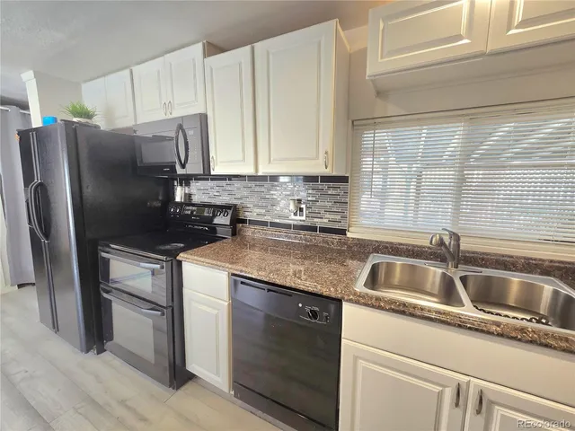 a kitchen with granite countertop a sink and a refrigerator
