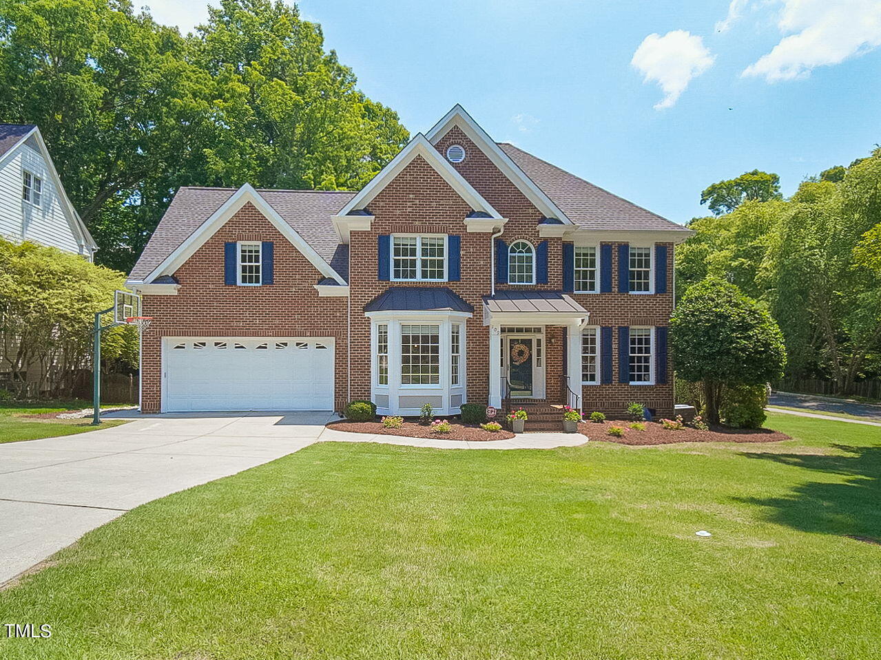 a front view of a house with garden and trees