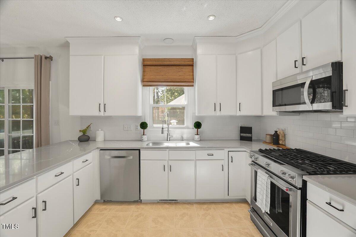 9813 Rockledge Drive Raleigh, NC 27617 - Photo 13 of 52 a kitchen with granite countertop white cabinets sink and stainless steel appliances