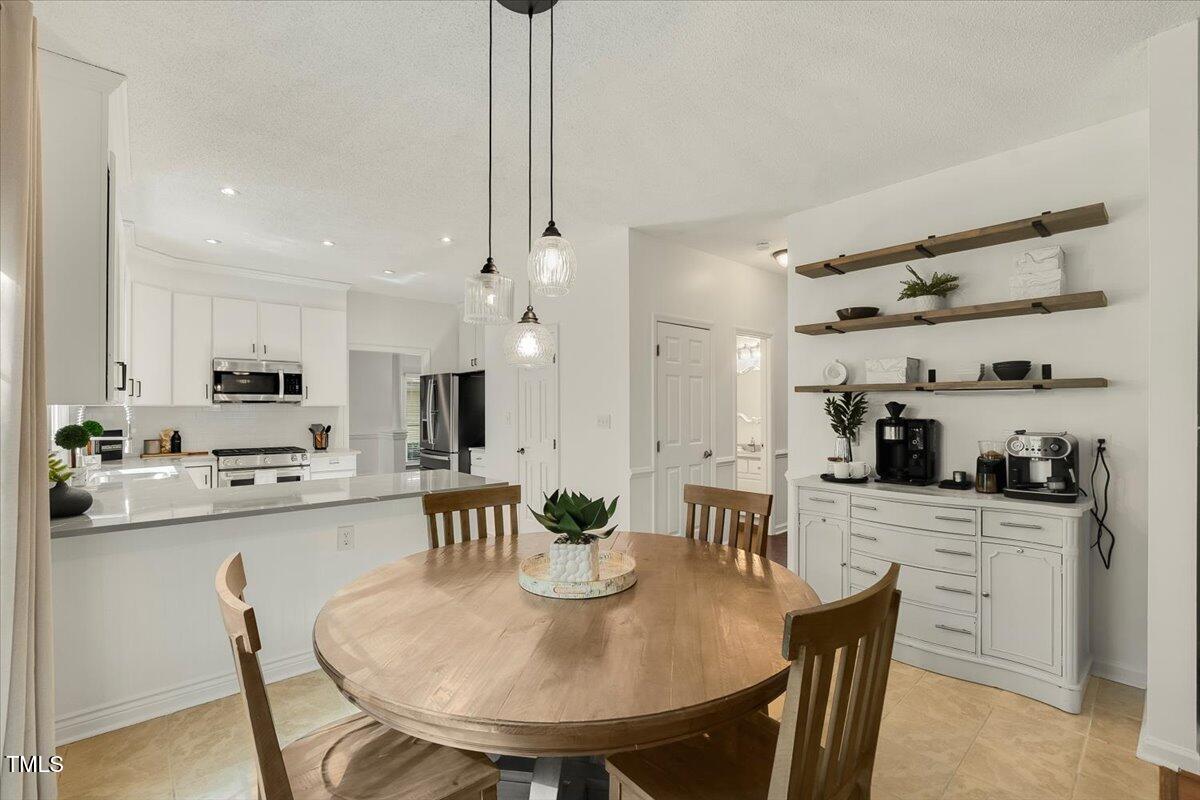 9813 Rockledge Drive Raleigh, NC 27617 - Photo 19 of 52 a kitchen with kitchen island a dining table and chairs