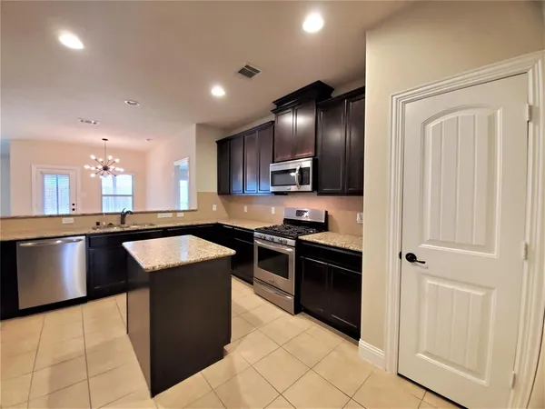 a kitchen with stainless steel appliances kitchen island granite countertop a stove a sink and a refrigerator