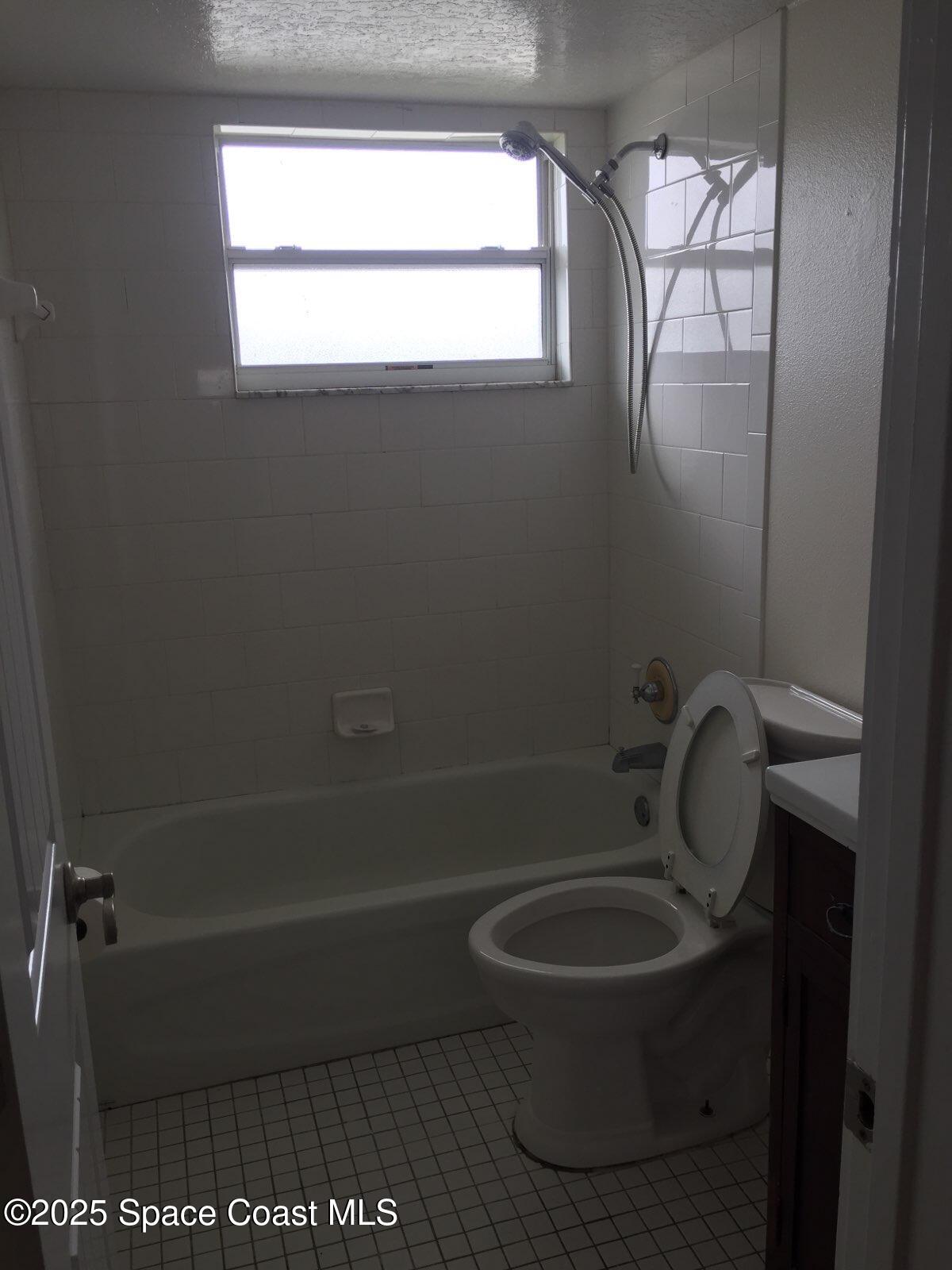 307 Adams Avenue, Unit 14 Cape Canaveral, FL 32920 - Photo 9 of 9 a bathroom with a toilet a window and a glass door