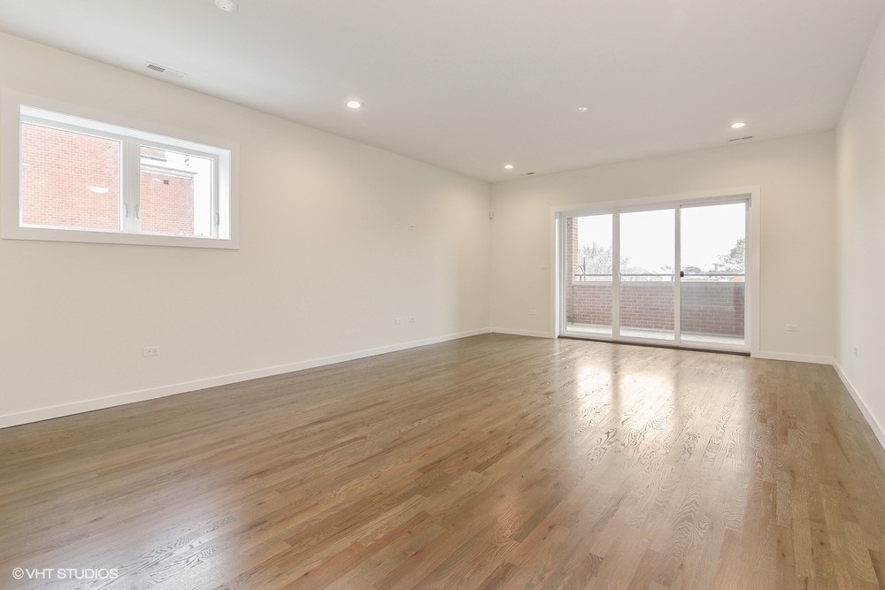 3326 West Irving Park Road, Unit 3W Chicago, IL 60618 - Photo 6 of 15 a view of an empty room with wooden floor and glass window