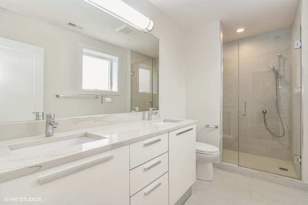3326 West Irving Park Road, Unit 3W Chicago, IL 60618 - Photo 8 of 15 a bathroom with a granite countertop sink a toilet and shower