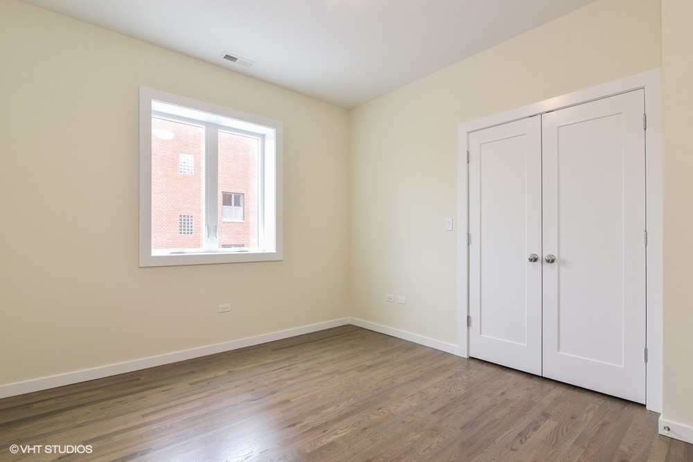 3326 West Irving Park Road, Unit 3W Chicago, IL 60618 - Photo 9 of 15 a view of an empty room with wooden floor and a window