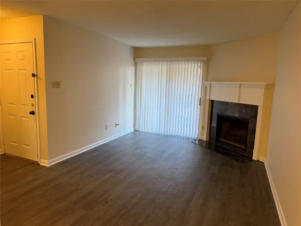 an empty room with wooden floor fireplace and windows